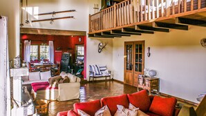 A spacious living room with a red sofa, wooden flooring, and a high ceiling. - Pet friendly home in Navarredonda de Gredos (Navarredonda de Gredos)