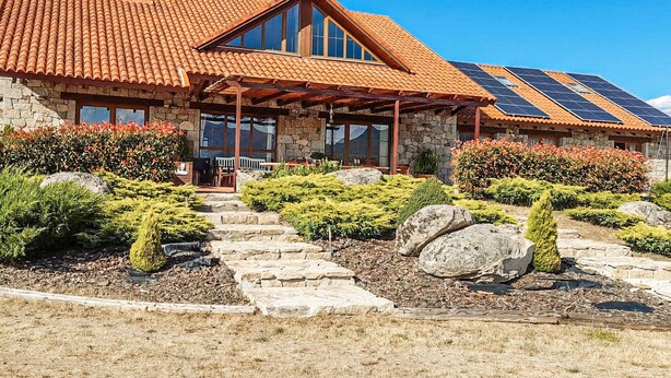 A stone building with a red-tiled roof, large windows, and solar panels. - Pet friendly home in Navarredonda de Gredos (Navarredonda de Gredos)