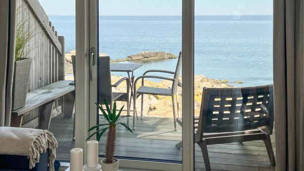 Een terras met uitzicht op zee, een stoel, een tafel en een potplant.
