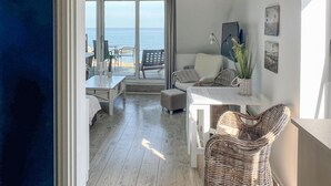 Een moderne kamer met balkon, een witte bank, een rieten stoel en een eettafel.