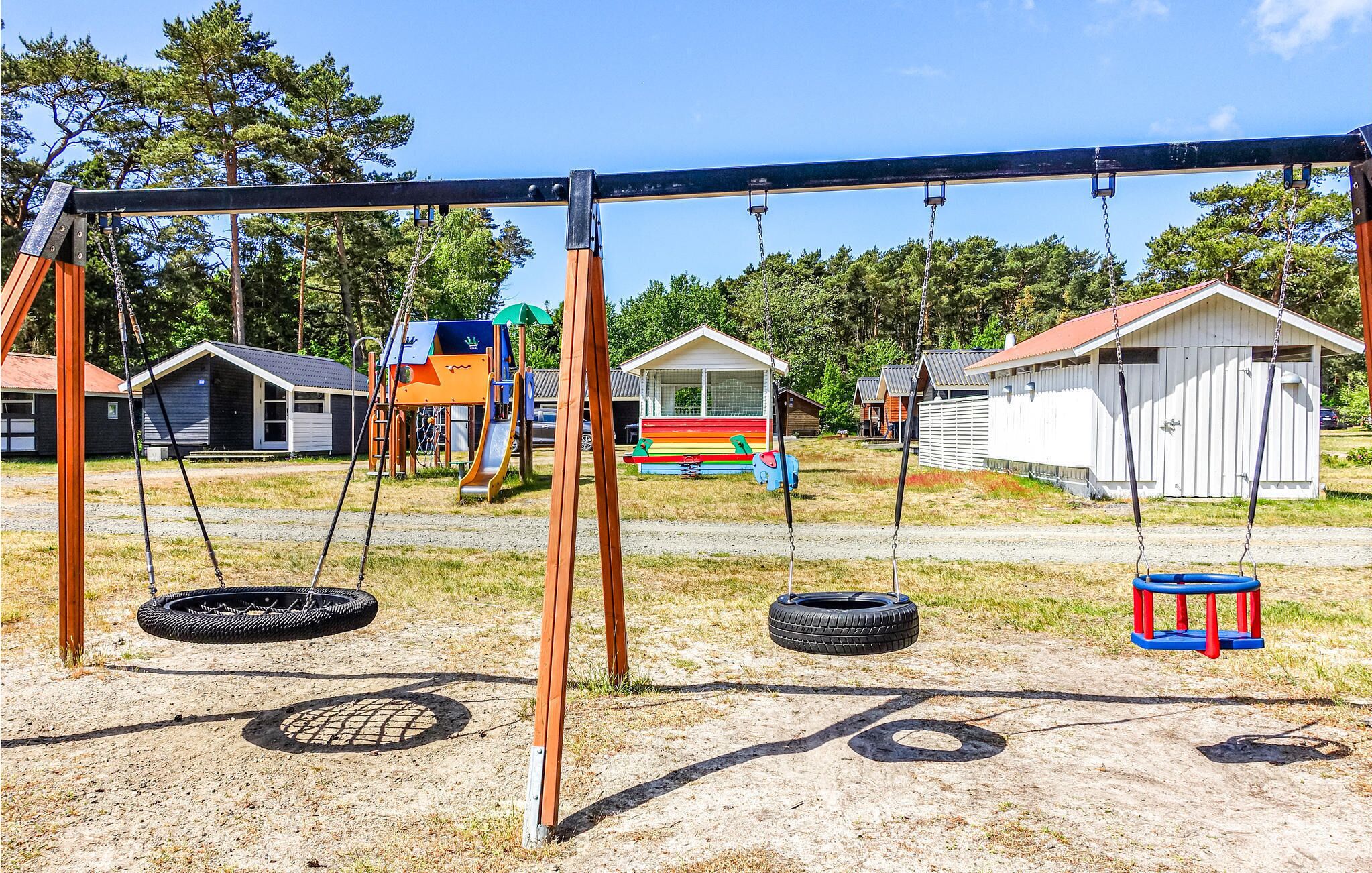Une aire de jeux avec des balançoires, des pneus suspendus et un toboggan.