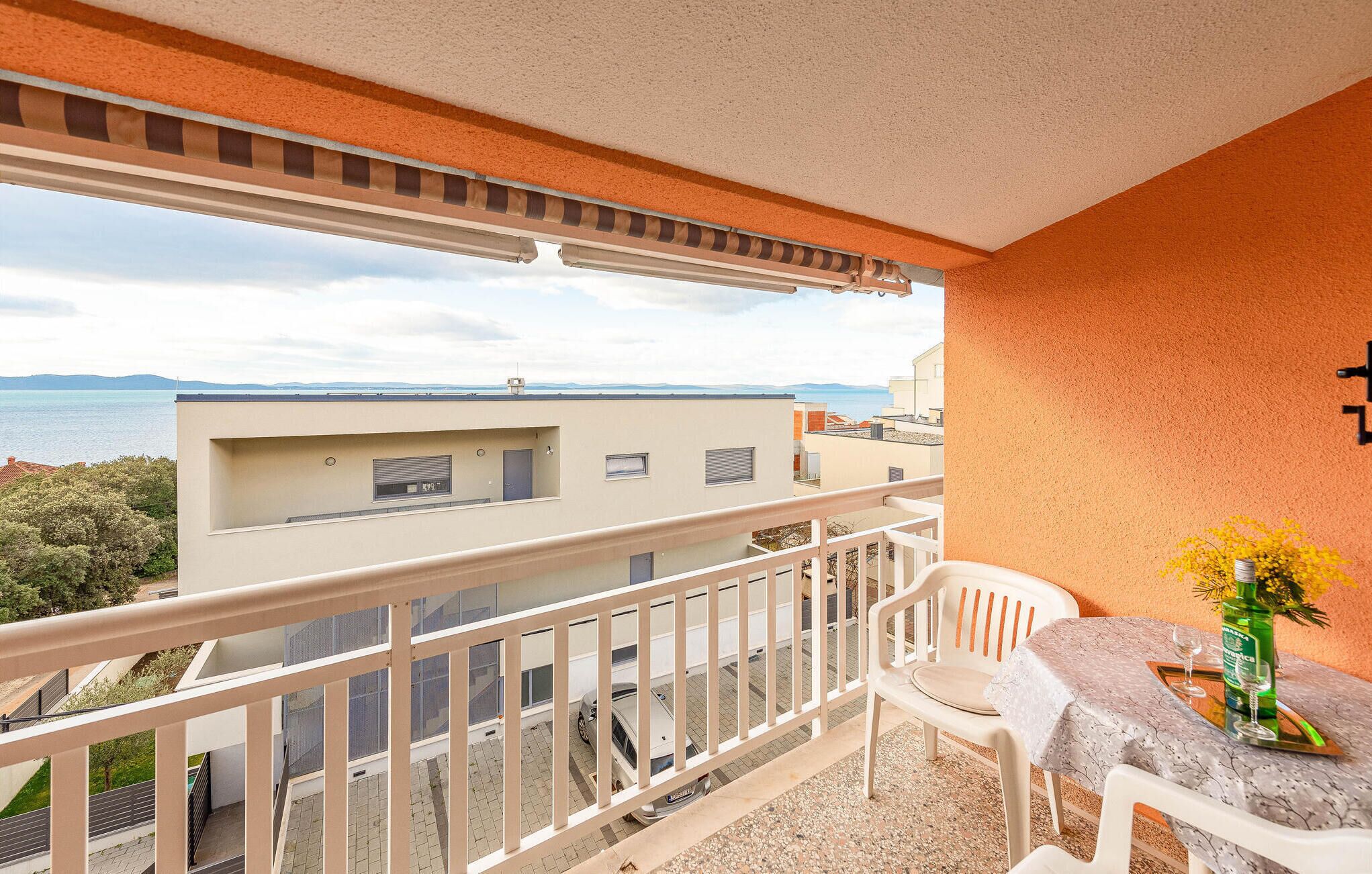 Un balcón con vistas al mar, una mesa con un florero y una silla.