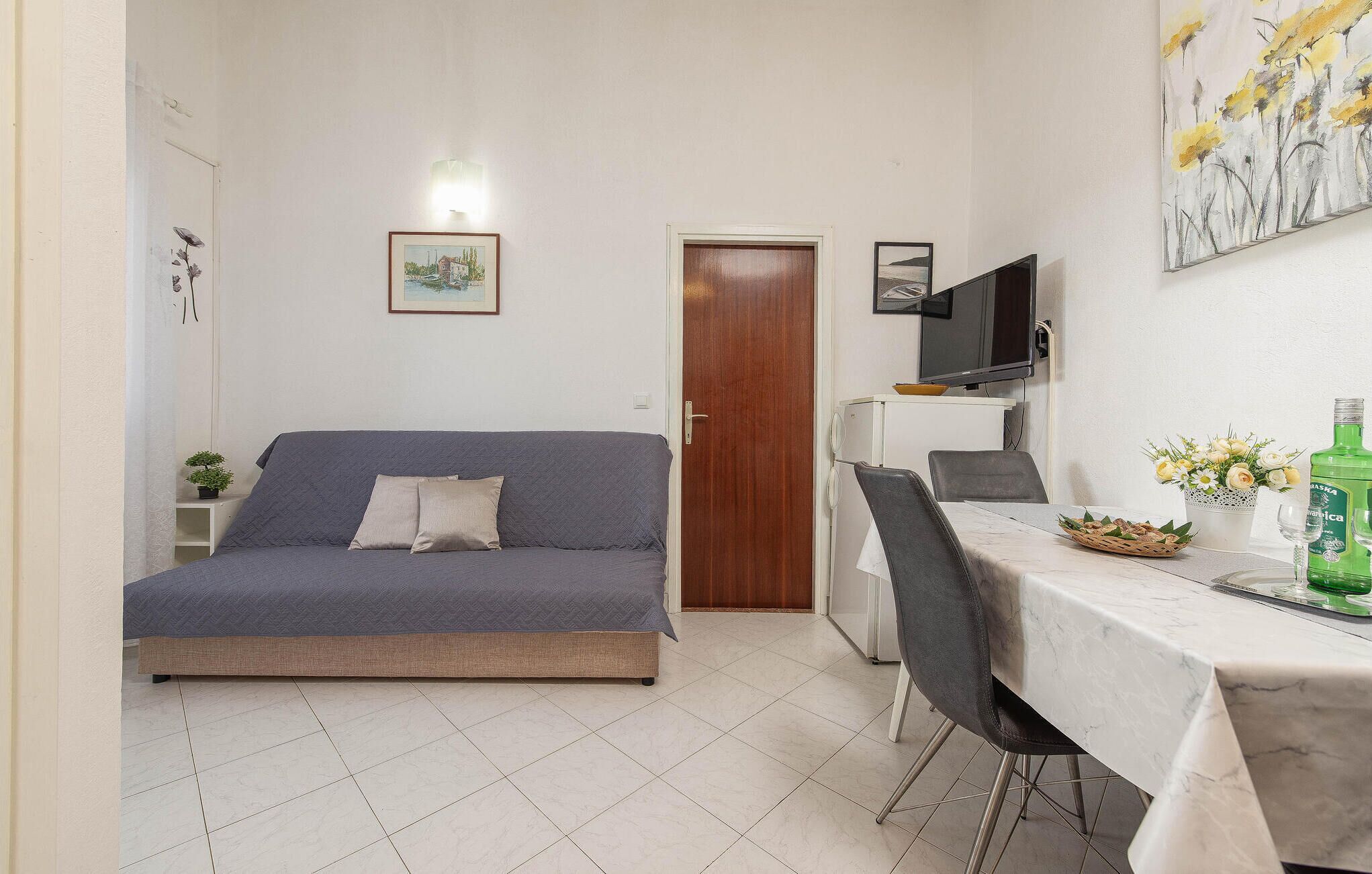 Un espacio habitable compacto con un sofá, una mesa de comedor, un televisor y una puerta.