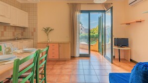 Cocina compacta con comedor, televisor y balcón con vistas.