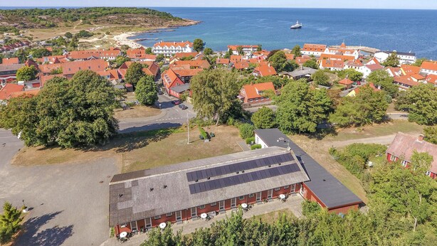 An aerial view of a coastal town with red-roofed buildings, a marina, and a large building with solar panels. - Nice apartment in Allinge with WiFi (Allinge)