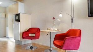 A modern kitchen with a microwave, a refrigerator, and a dining area with two red chairs and a small table.