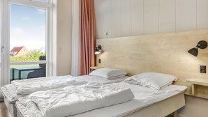 A bedroom with a large bed, a nightstand, a wall-mounted lamp, and a view of the outdoors. - Nice apartment in Allinge with WiFi (Allinge)