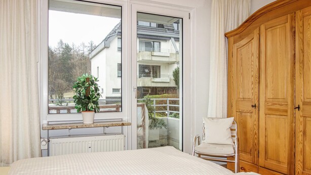 A hotel room with a bed, a potted plant, a chair, and a wooden wardrobe. - Awesome apartment in Goslar with WiFi (Goslar)