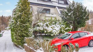 A red car parked in front of a house with a sloped roof and snow-covered trees. - Awesome apartment in Goslar with WiFi (Goslar)