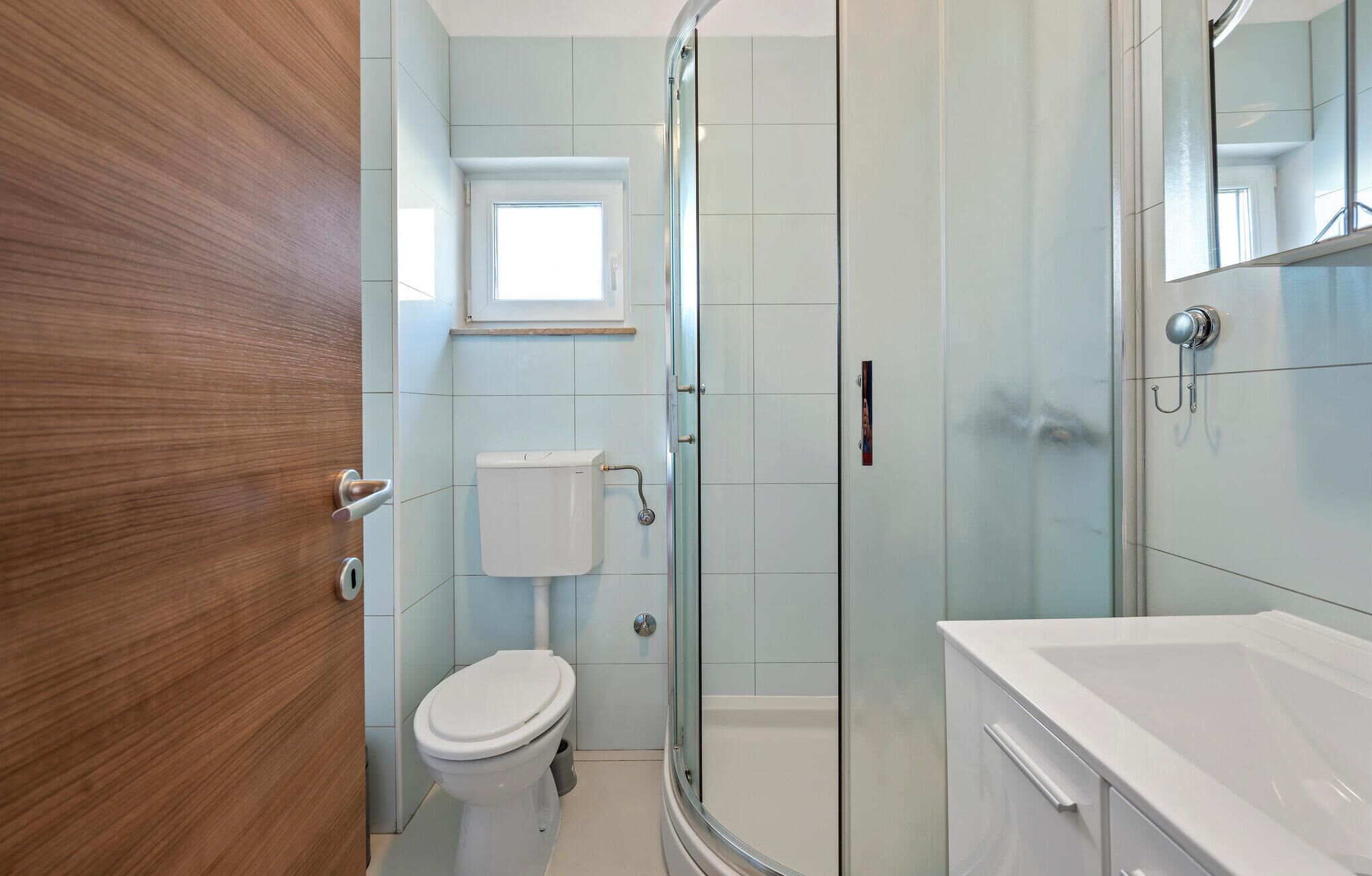 Un baño moderno con cabina de ducha de vidrio, inodoro y lavamanos blancos.