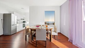 Une cuisine moderne avec des meubles blancs et un coin repas comprenant une table et des chaises.