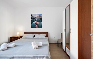 A bedroom with a bed, a nightstand, a wooden wardrobe, and a painting of a mountain landscape. - Beach front home in Primosten with house sea view (Primosten)