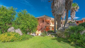 A multi-story building with a garden area, including a lawn and various plants. - 1 bedroom cozy apartment in Palau (Palau)