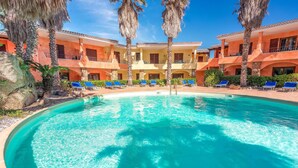 A pool surrounded by palm trees and a building with multiple balconies. - 1 bedroom cozy apartment in Palau (Palau)