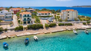 A coastal residential area with houses, clear blue sea, and boats. - 2 bedroom beach front apartment in Rogoznica (Rogoznica)