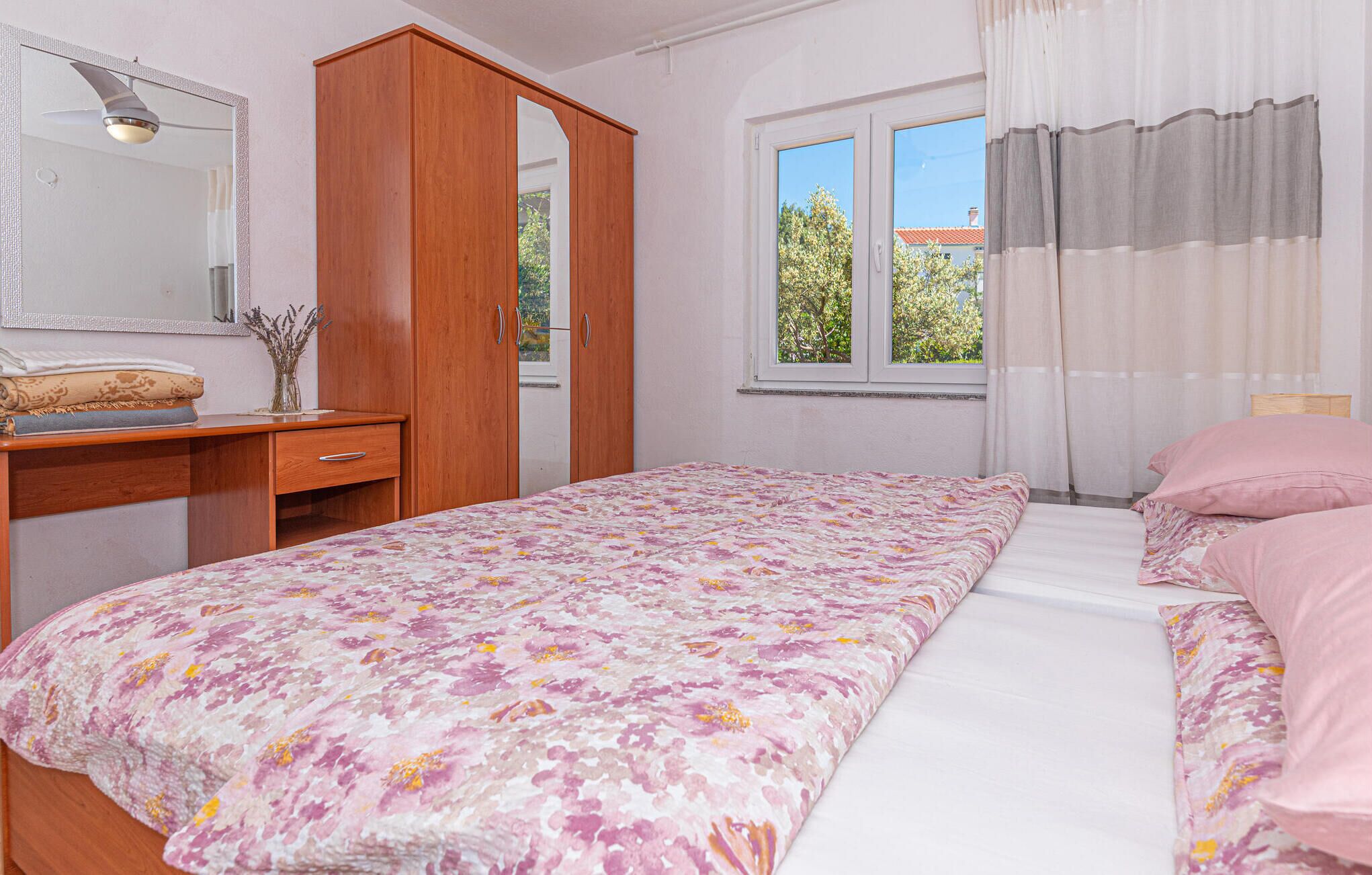 A bedroom with a bed, a wardrobe, a desk, and a window with curtains.