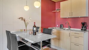 A modern kitchen with a granite countertop, a wine bottle, and a vase with flowers.