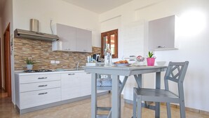 A modern kitchen with white cabinets, a gas stove, and a tiled backsplash. - Lovely home in Laureana Cilento (Laureana Cilento)