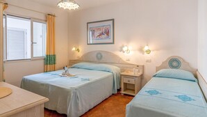 Ein Hotelzimmer mit zwei Betten, einem kleinen Tisch und einem Fenster mit Vorhängen.