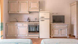 Eine kleine Küche mit Holzausstattung, einem Kühlschrank, einem Backofen und einem Fernseher.