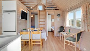 A cozy cabin interior with a dining area, kitchen, and a loft bedroom. - Amazing home in Struer with kitchen (Struer)