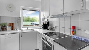 A modern kitchen with white cabinets, a black countertop, a built-in oven, and a window with a view of greenery. - 1 bedroom nice home in Rønne (Rønne)