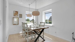 A dining area with a wooden table, white chairs, and pendant lights. - 1 bedroom nice home in Rønne (Rønne)