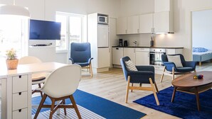 A modern apartment with a kitchen, dining area, and living room. It includes a flat-screen TV, a microwave, a refrigerator, a coffee maker, and a dining table with chairs. - Amazing apartment in Nexø with kitchen (Nexø)