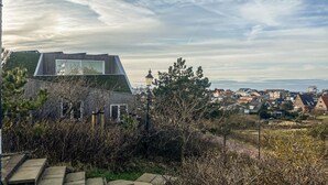 Un bâtiment moderne doté d’un toit en pente et de grandes fenêtres, entouré d’arbres et offrant une vue sur un quartier résidentiel.