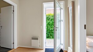 Ein Flur mit einer Schiebetür zu einem Garten, einem weißen Heizkörper und einer schwarzen Fußmatte vor der Tür.
