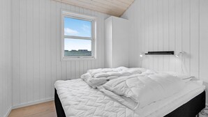 Ett sovrum med en säng, ett fönster och en väggmonterad lampa.