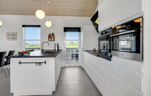 Una cocina moderna con una isla central, horno empotrado y vistas al exterior.