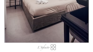 Ein modernes Schlafzimmer mit einem großen Bett, einem dunklen Kleiderschrank, einem kleinen Tisch und einem Wandbild mit Booten auf dem Wasser.