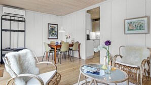 A modern living room with wicker furniture, a dining area with a wooden table, and a kitchen in the background. - Amazing home in Gudhjem with WiFi (Gudhjem)