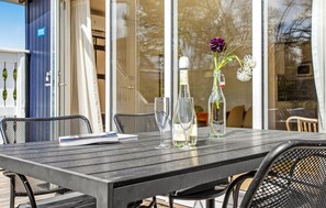 A wooden table with two wine glasses, a bottle of Sparklettner, and a vase with flowers. - Beach front home in Gudhjem with WiFi (Gudhjem)