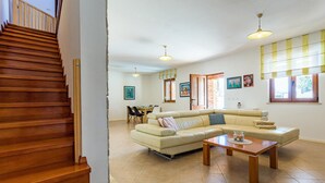 Ein geräumiges Wohnzimmer mit einem beigefarbenen Sofa, einem Holztisch und einem Essbereich im Hintergrund.