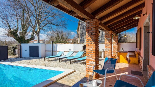 Ein überdachter Außenbereich mit Pool, Liegestühlen und einem Tisch mit einer Tasse.