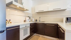 Eine moderne Küche mit weißen Schränken, einer Spüle aus Edelstahl, einer Mikrowelle und einem Backofen.