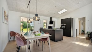 Een moderne keuken met een centraal eiland, hanglampen en uitzicht op de omgeving.