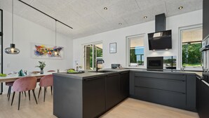 Een moderne keuken met een centraal eiland, zwarte kastjes en een groot raam met uitzicht op groen.