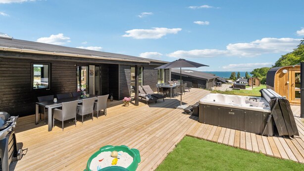 Een modern terras buiten met een jacuzzi, lounge stoelen en een barbecue.