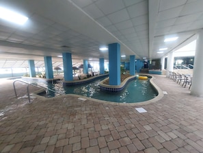 An indoor swimming pool with blue pillars, a brick floor, and a yellow float.
