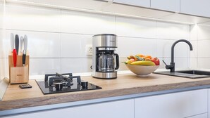 Una cocina moderna con cafetera, frutero y bloque de cuchillos.