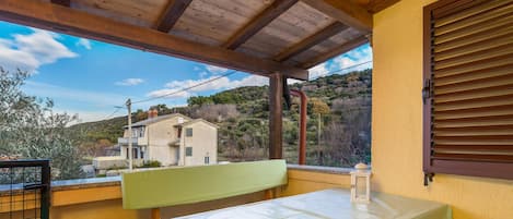 Ein Balkon mit Tisch und Stühlen, Blick auf ein Haus und Holzbalkendecke.