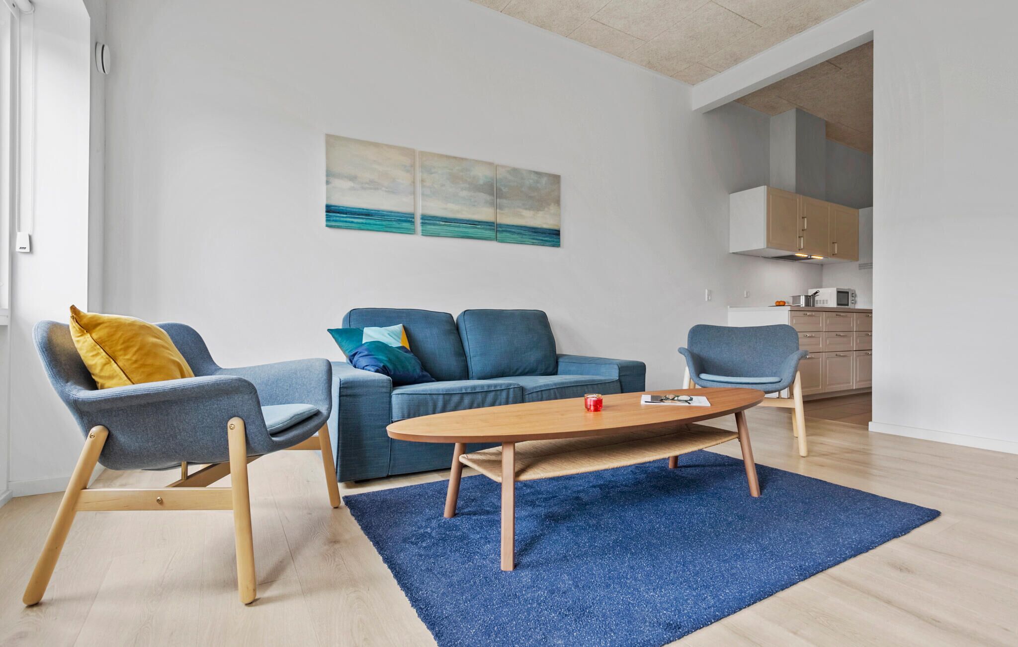A modern living room with a blue sofa, a blue armchair, and a wooden coffee table.