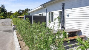 Une rangée de maisons mobiles, avec une allée en gravier et une rangée d’arbustes verts devant.