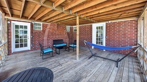 A covered patio with wooden beams, red brick walls, and a hammock. - Pure GOLD on Emerald Isle - 4BR, Patio, WIFI (Jacksonville)