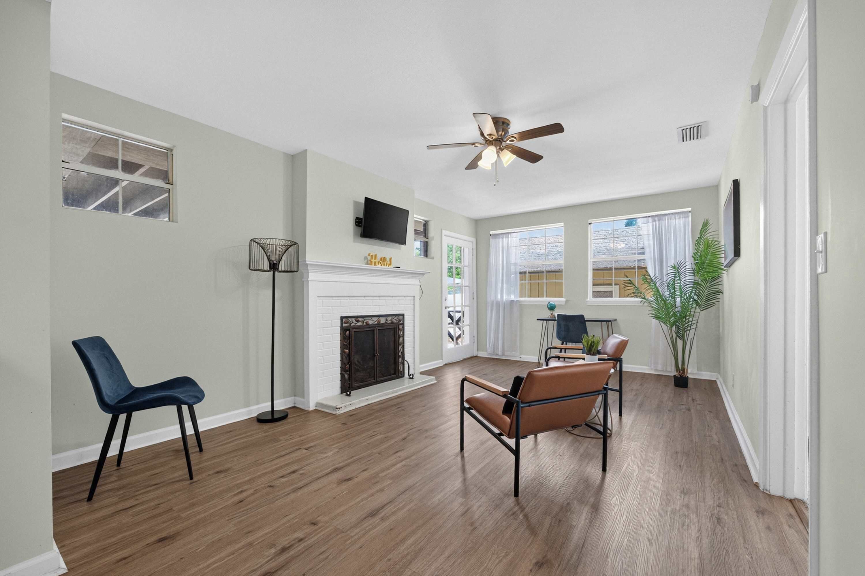 A living room with a fireplace, a ceiling fan, and a dining area with chairs and a table.