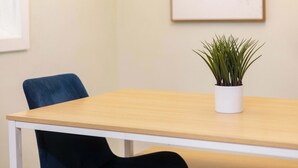 A conference room with a wooden table, two blue chairs, a white potted plant, and a framed artwork on the wall. - Pure GOLD on Emerald Isle - 4BR, Patio, WIFI (Jacksonville)