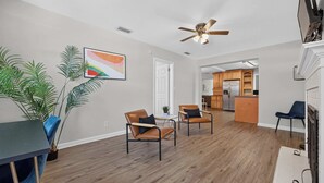 A spacious living area with a ceiling fan, a dining table, two chairs, and a potted plant. - Pure GOLD on Emerald Isle - 4BR, Patio, WIFI (Jacksonville)